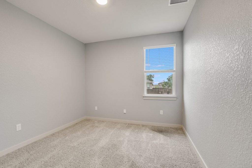 Bedroom 3 in the middle of the home with a window overlooking the side yard.